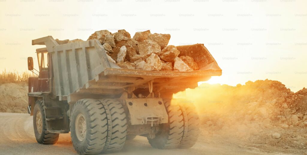 Open-pit mine at dusk with dump truck and floodlights — oil price impact on mining operations